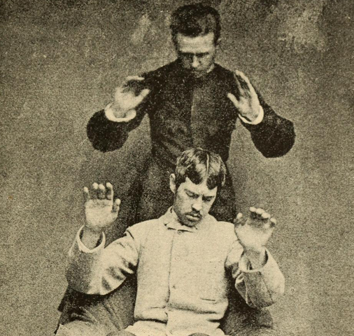 Detail from a depiction of thought-transference, the man behind dictating the movement of the other, from Magnetismus und Hypnotismus (1895) by Gustav Wilhelm Gessmann
